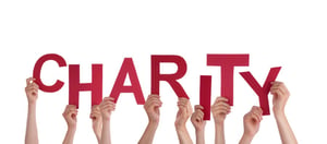 hands holding up paper letters with charity written on it